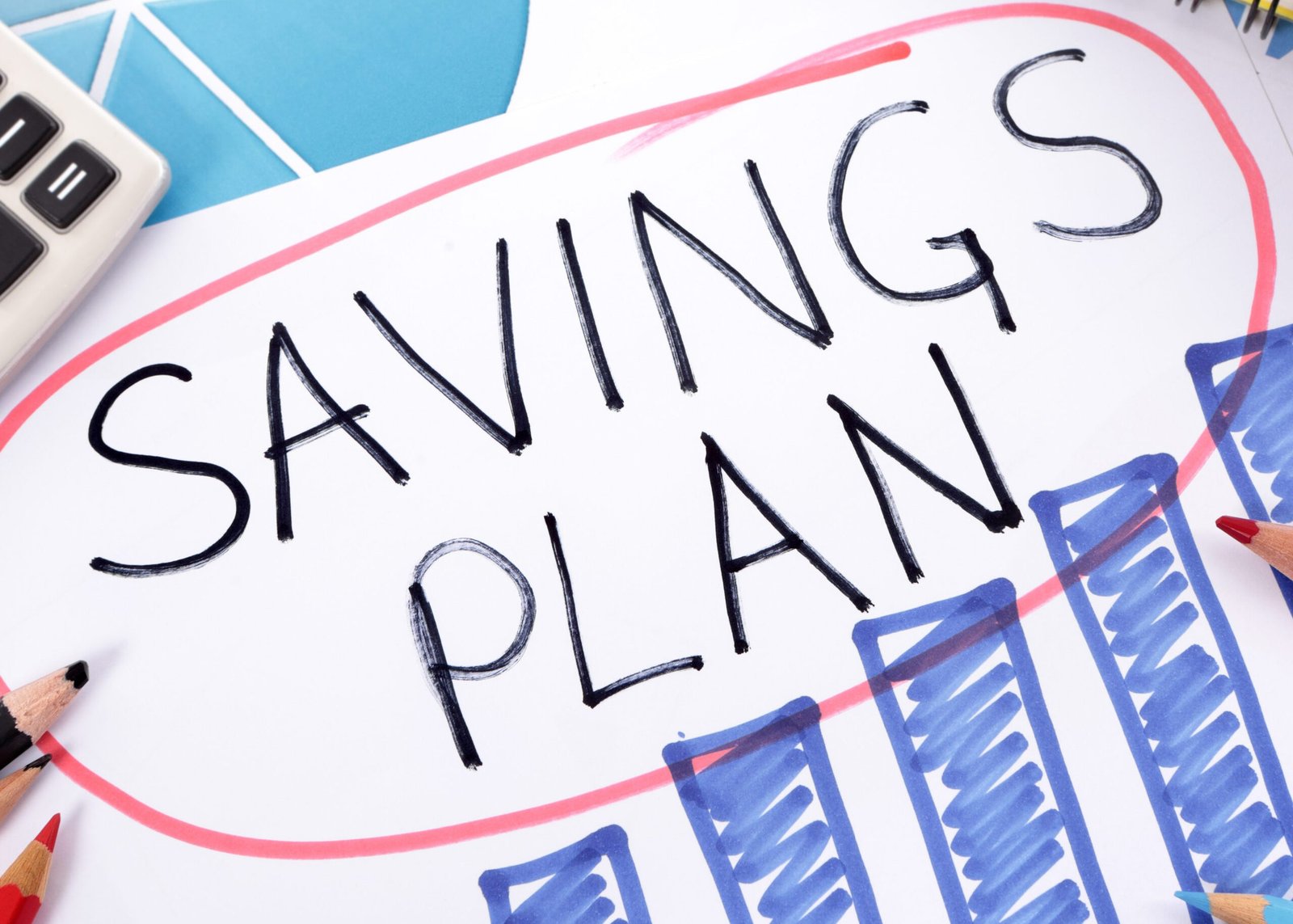 The words Savings Plan written on a hand drawn bar chart surrounded by pencils, books and calculator.